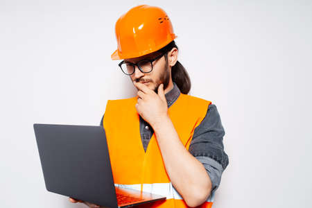 Portrait of young engineer looking in laptop on white background.の写真素材