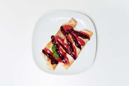 Vegan dessert. Rolled pancakes with berry cream topping, on the white plate.の写真素材
