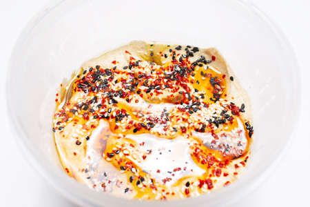 Vegan food. Close-up of homemade hummus with olive oil and spices, on white.
