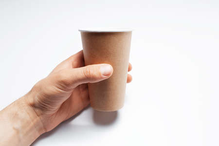 Close-up of male hand holding paper coffee cup on studio white background.の写真素材