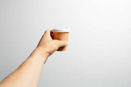 Close-up of male hand holding a small paper cup of coffee takeaway, on white.の写真素材