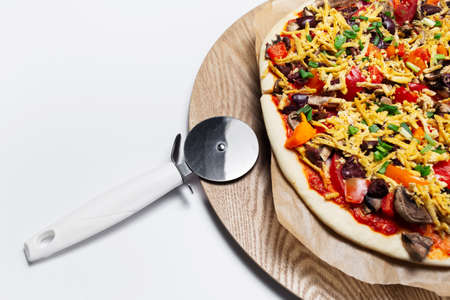 Close-up of homemade vegan pizza and knife on wooden table and white background.の写真素材