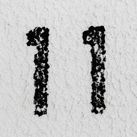 Close-up of black painted number of 11 on background of grey textured wall.の写真素材