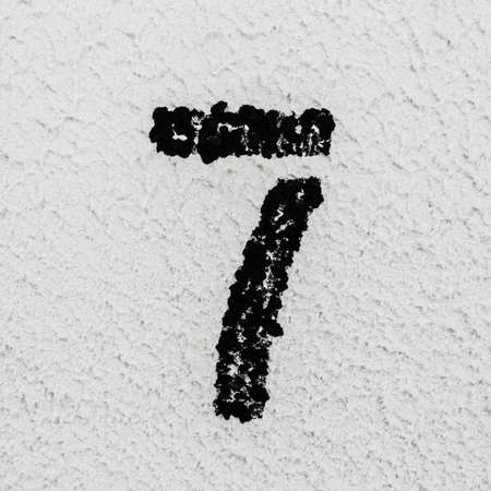 Close-up of black painted number of 7 on background of grey textured wall.の写真素材
