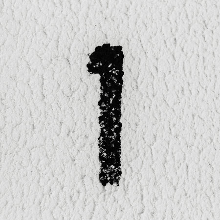 Close-up of black painted number of 1 on the grey textured wall.の写真素材
