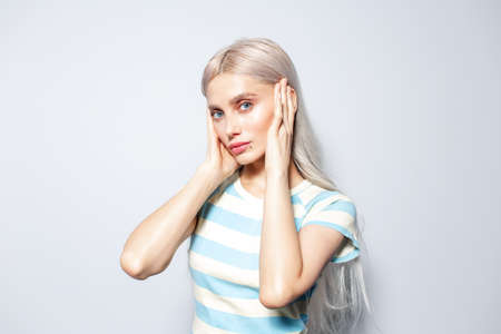 Portrait of pretty, fashion blonde girl in striped shirt on white background.