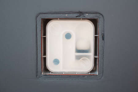Close-up of siphon for air conditioner drainage on grey wall.