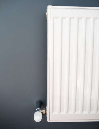 Close-up of steel heating radiator of white on a grey wall.の写真素材