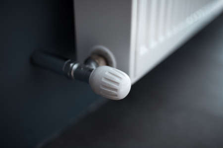 Close-up of valve of heating radiator of white on a grey wall.の写真素材