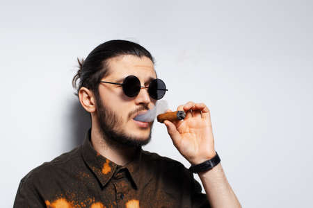 Close-up studio portrait of young man with a cigar on white background.の写真素材