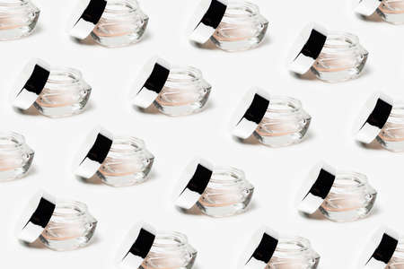 Pattern of transparent opened cosmetic jar near cap on white background.の写真素材