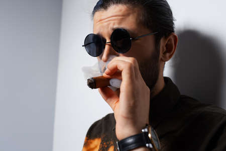 Close-up studio portrait of young man with a cigar on white background.の写真素材