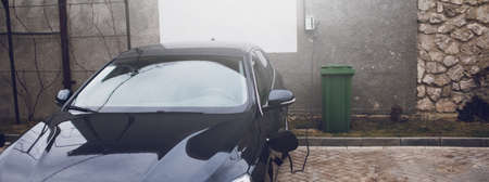 Plug-in hybrid EV car charging at charge station, home. Panoramic banner view.の写真素材