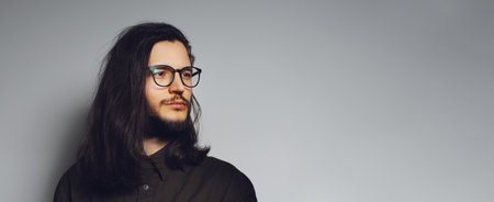 Portrait of young man with long hair and glasses. Panoramic banner. Copy space.の写真素材