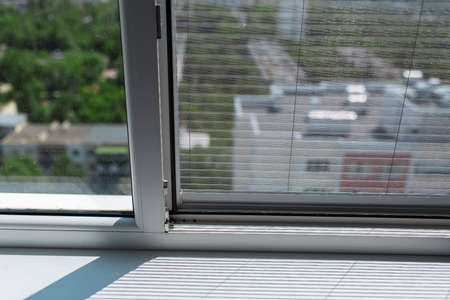 Close-up of plastic window with modern mosquito net. Sunny day.