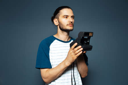 Studio portrait of young man photographer making photo with polaroid camera.