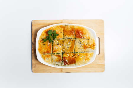 Close-up top view of greek pie spanakopita on wooden board. Homemade vegan food.