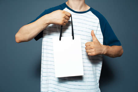 Studio portrait of young man, holding a white reusable bag and showing thumb up.の写真素材