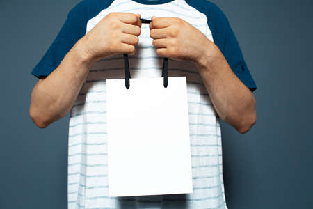 Studio portrait of young man, holding a white reusable bag.