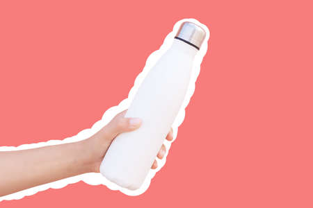 Reusable thermo water bottle in hand, isolated with white contour on red.の写真素材
