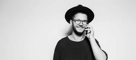 Panoramic banner portrait of young smiling man talking on smartphone on white background with copy space.の写真素材