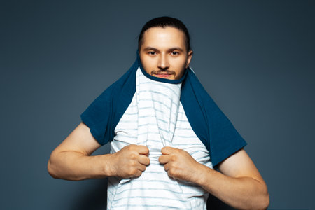 Studio portrait of man dressing the shirt on blue background.の写真素材