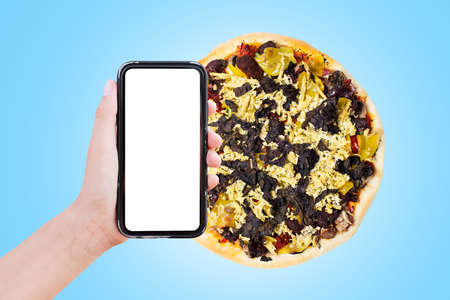 Close-up of male hand holding smartphone with empty blank on screen, on background of pizza isolated...