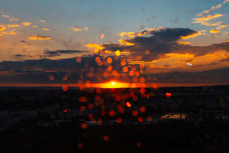 Close-up of blurred raindrops, bokeh on window, focus on sunset. Natural abstract background.の写真素材