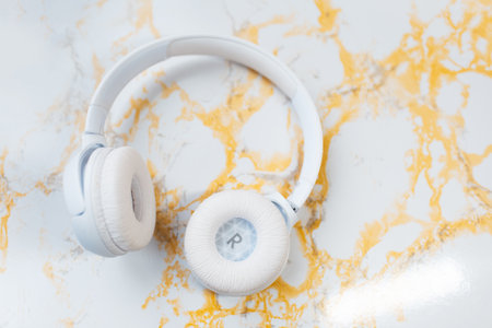 Close-up top view of wireless headphones on background of white yellow marble.