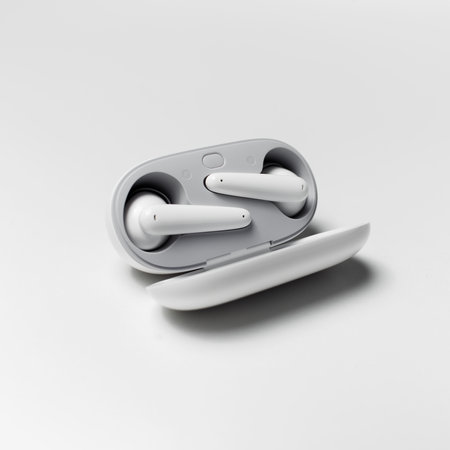 Close-up of modern wireless earphones lying in charger case on white studio background.