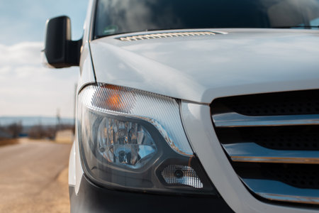 Close-up of headlight of white car outdoors.