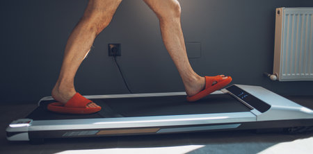 Close-up of male legs in slippers who runs on treadmill.
