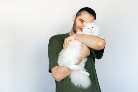 Portrait of young happiness man hugging white fluffy cat with blue eyes on white background.の写真素材