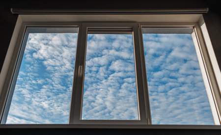 View of blue sky and white clouds thorough window.