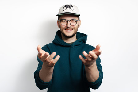 Young smiling guy looking at camera with wide open hands isolated on white background.の写真素材