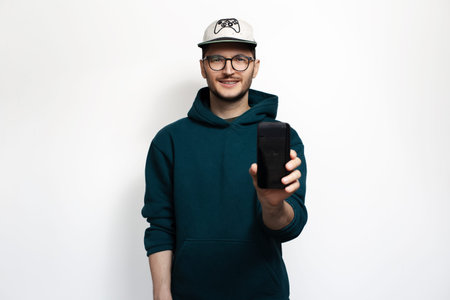 Smiling young man showing smartphone isolated on white background.