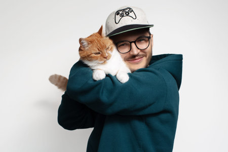 Happy young man hugging his cat, isolated on white background