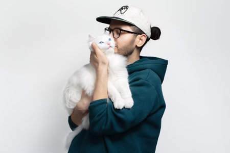happy young man kissing his white cat isolated on white background.