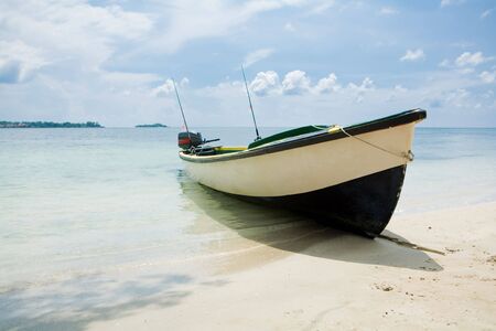 Fishing boat on a beach with water and blue skies