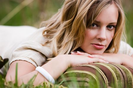 Blonde Woman lying on the grass on her stomach with a pillowの写真素材