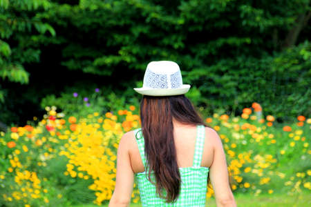 Young girl with a green dress and a hat in the gardenの写真素材