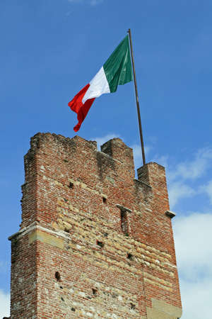Italian flag flying high above an ancient tower of a castle in Italy の写真素材