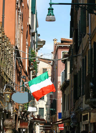 Venetian street crowded with shops and Italian flagの写真素材