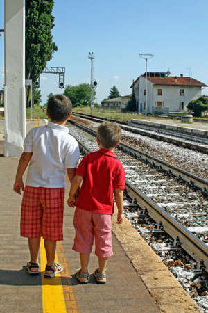 two children waiting for the train on the tracks to the stationの写真素材