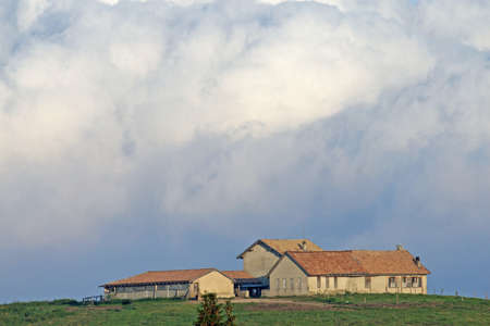 Stable over the hill with huge white clouds in the backgroundのeditorial素材