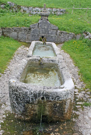 old stone fountain with watering and tanks for washing clothes のeditorial素材