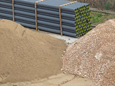 piles of land and stones mined by excavation in construction site and pipesのeditorial素材