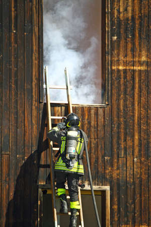 firefighters with oxygen cylinder to peg up the ladder to extinguish a dangerous fire with white smokeのeditorial素材