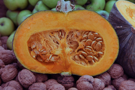 orange pumpkin cut in half with the seeds of pumpkin and many nuts on the backgroundの写真素材