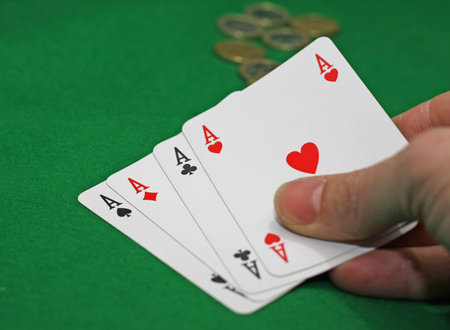 hand with poker of aces on a green table game